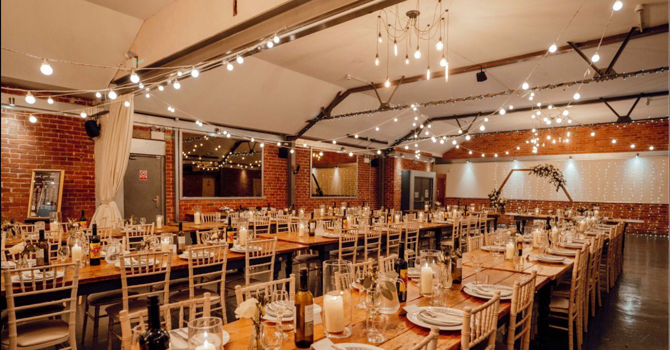 Warm string-lit banquet venue with long dining tables