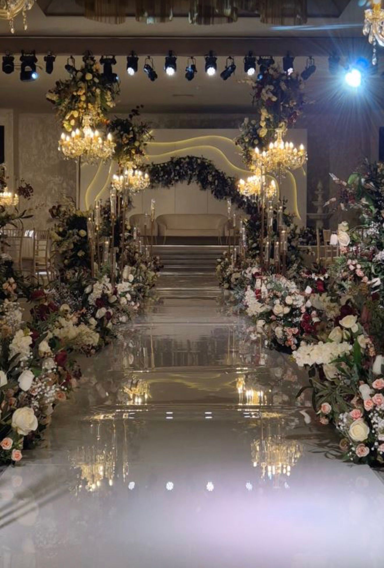 Floral ceremony aisle with chandeliers and stage